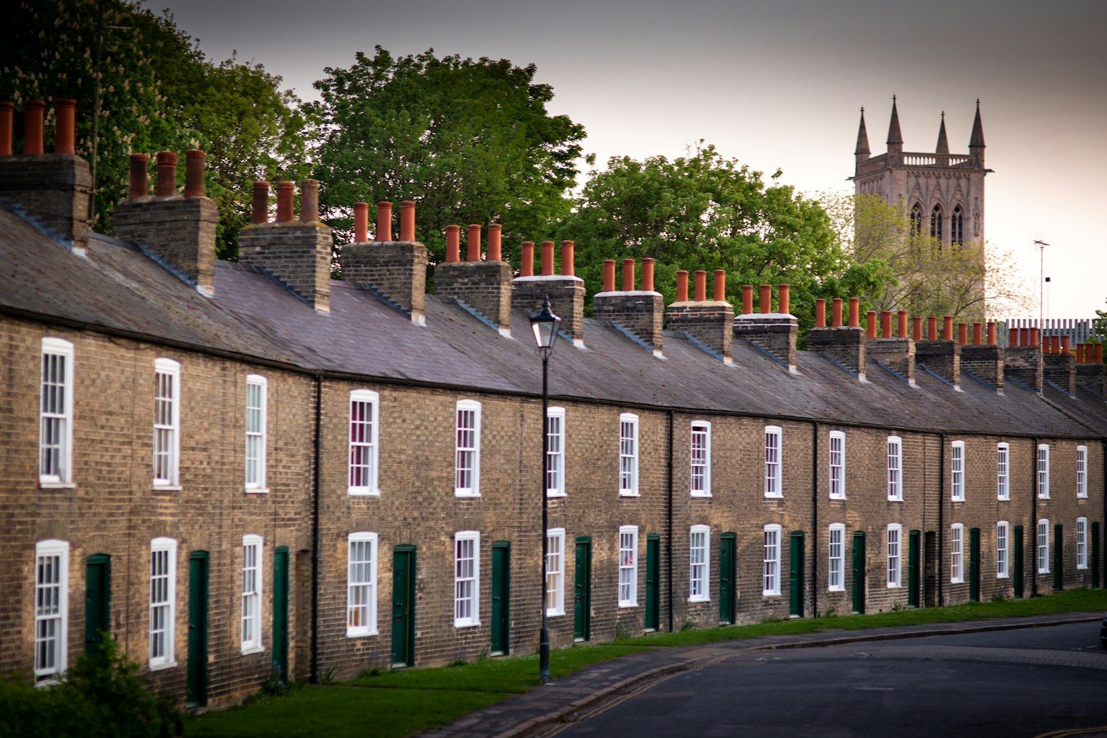 A long terrace of red-brick houses with chimneys under a bright sky